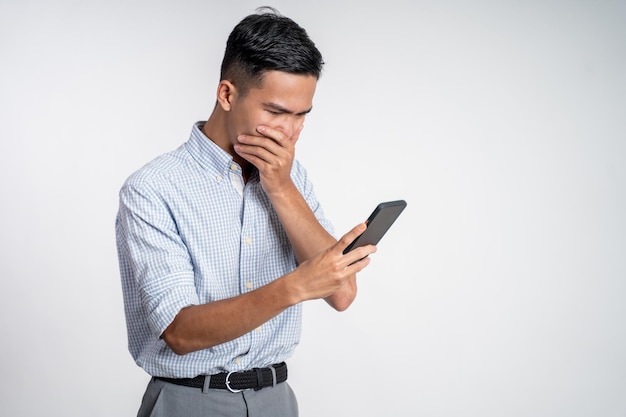 Giovane uomo asiatico scioccato mentre guardava lo schermo dello smartphone