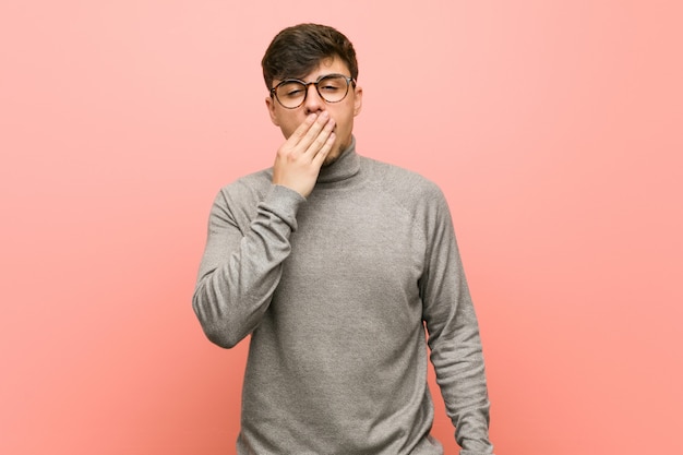 Giovane uomo astuto dello studente che sbadiglia mostrando una bocca stanca della copertura di gesto.