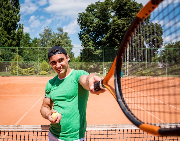 Giovane uomo atletico sul campo da tennis