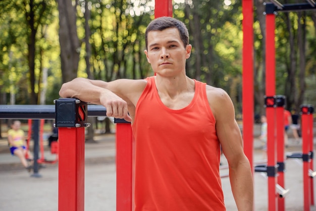 giovane uomo atletico va a fare sport nel parco fitness all'aperto stile di vita sano