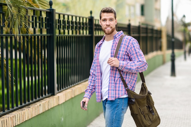 Giovane uomo barbuto che cammina nella priorità bassa urbana. Concetto di stile di vita.