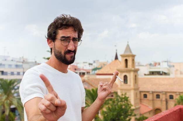 Giovane uomo barbuto che fuma una sigaretta