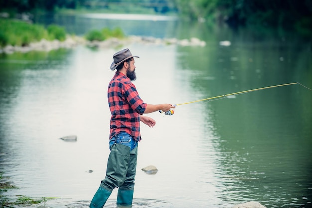 Giovane uomo barbuto che pesca in un lago o in un fiume Pesca a mosca