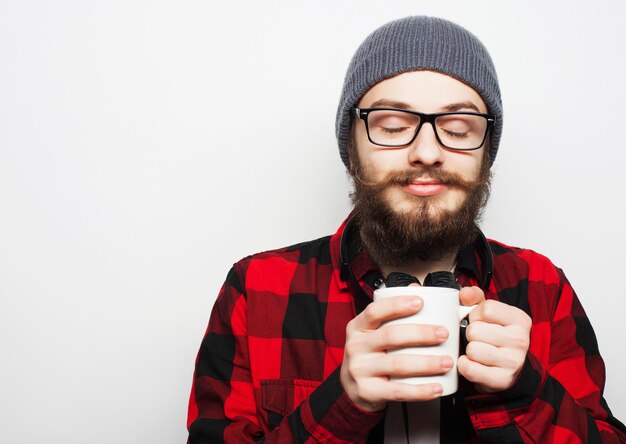 giovane uomo barbuto con una tazza di caffè su grigio