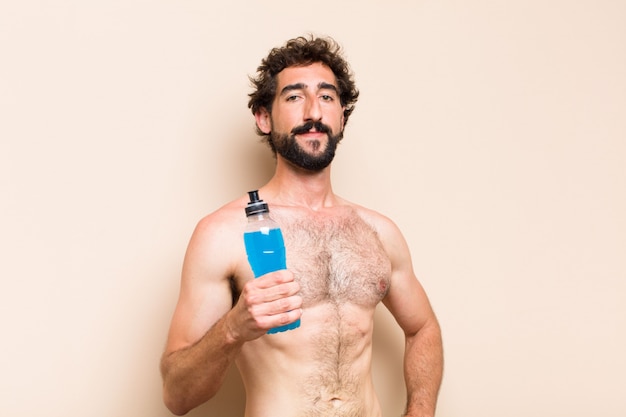 Giovane uomo barbuto freddo che beve un concetto di forma fisica della bevanda energetica