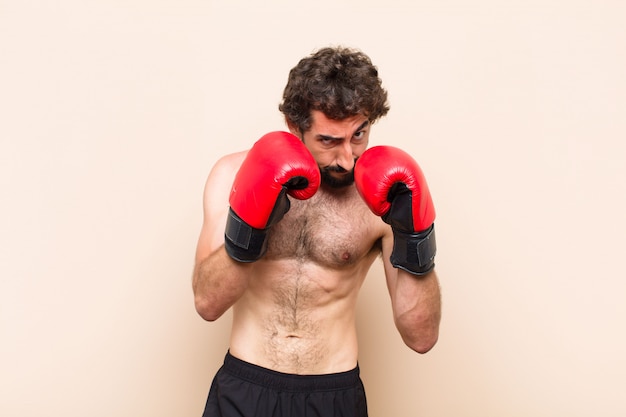 Giovane uomo barbuto freddo con guantoni da boxe e concetto di fitness di combattimento