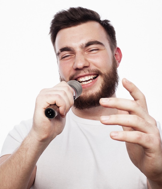 Giovane uomo barbuto in camicia bianca che canta nel microfono