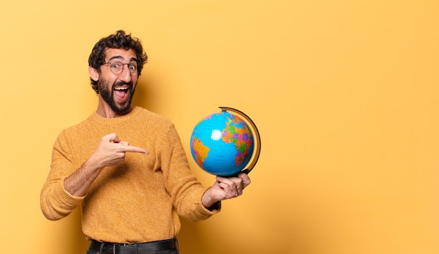 Giovane uomo barbuto pazzo che tiene una mappa del globo del mondo
