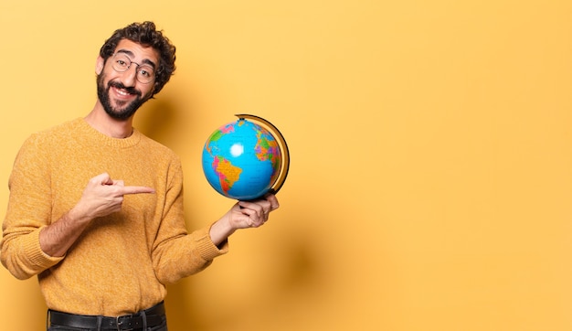 Giovane uomo barbuto pazzo che tiene una mappa del globo del mondo.