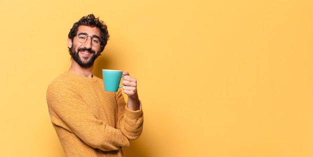 Giovane uomo barbuto pazzo con una tazza di caffè