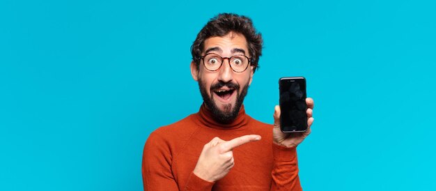 Giovane uomo barbuto pazzo. espressione scioccata o sorpresa. concetto di smartphone