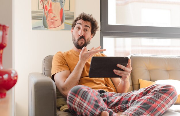 Giovane uomo barbuto su un divano con un tablet touch screen