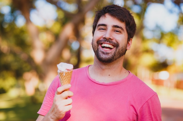 Giovane uomo bello che mangia il gelato nel parco