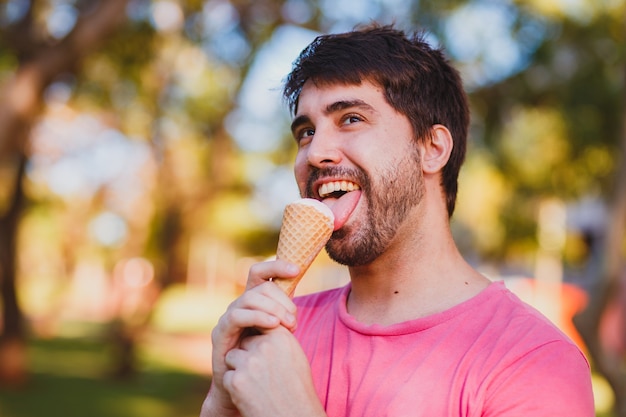 Giovane uomo bello che mangia il gelato nel parco