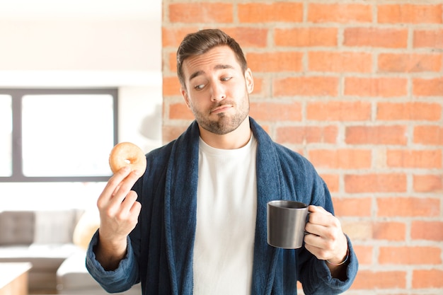 Giovane uomo bello che mangia un caffè a casa