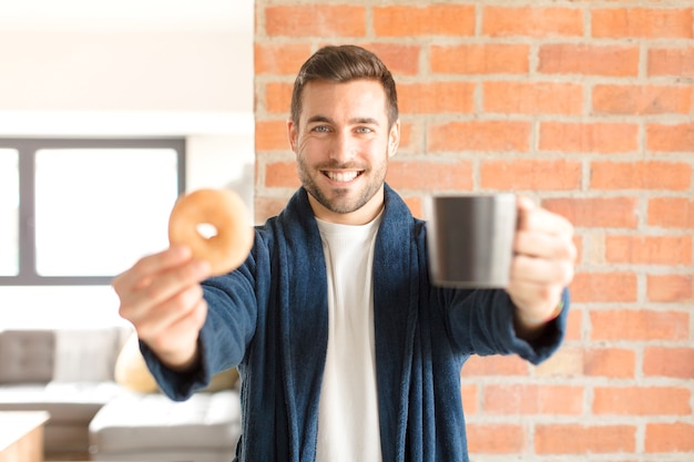 Giovane uomo bello che mangia un caffè a casa