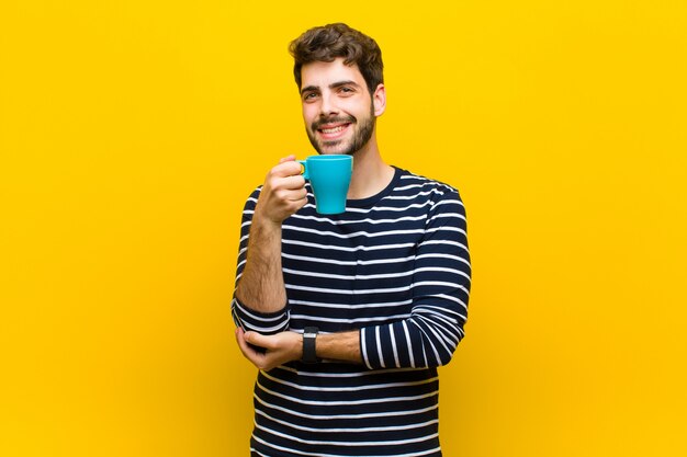 Giovane uomo bello che mangia un caffè