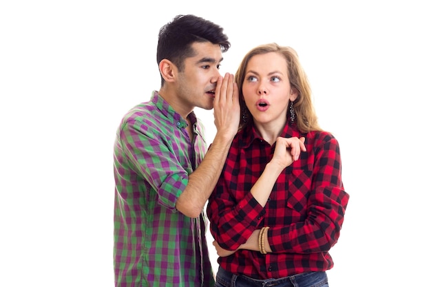 Giovane uomo bello che parla con una giovane donna sorpresa con lunghi capelli castani in camicia a quadri