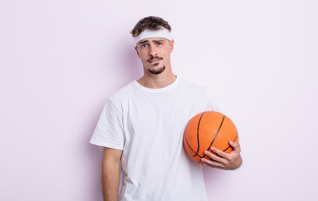 Giovane uomo bello che sembra perplesso e confuso. concetto di basket