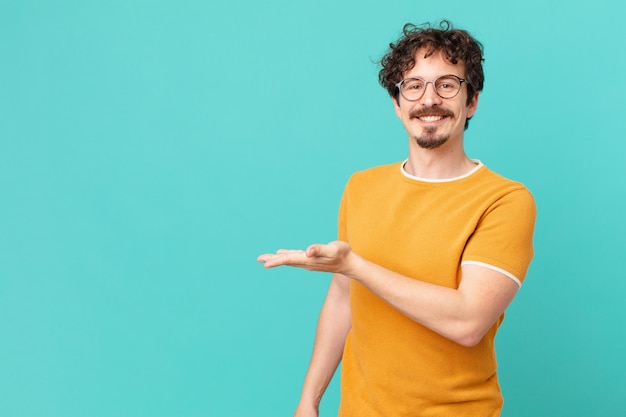 giovane uomo bello che sorride allegramente, sentendosi felice e mostrando un concetto