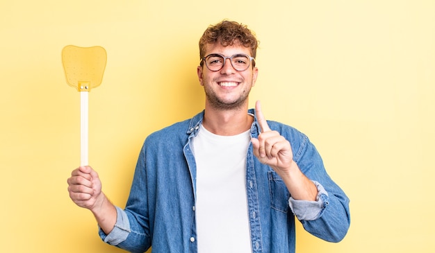 Giovane uomo bello che sorride con orgoglio e sicurezza facendo il numero uno. concetto di scacciamosche