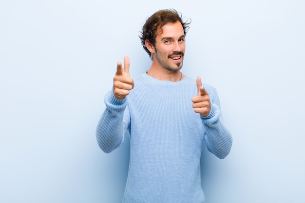 Giovane uomo bello che sorride con un indicare felice positivo di atteggiamento