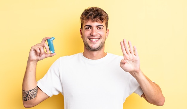 Giovane uomo bello che sorride e sembra amichevole, mostrando il numero quattro. concetto di asma