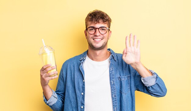 Giovane uomo bello che sorride e sembra amichevole, mostrando il numero quattro. concetto di frullato