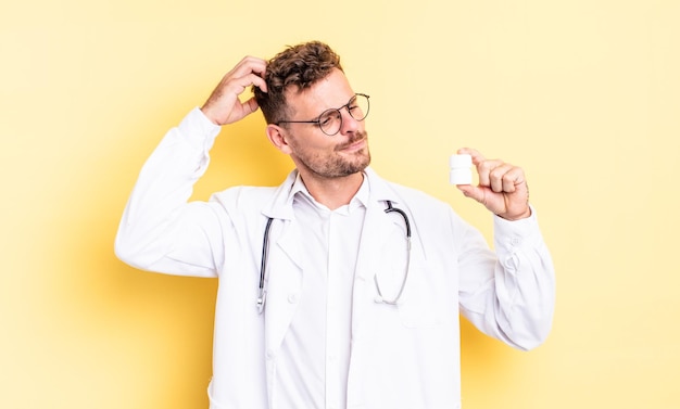 Giovane uomo bello che sorride felicemente e sogna ad occhi aperti o dubita. concetto di bottiglia di pillole medico