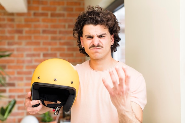 Giovane uomo bello che tiene un casco da moto all'interno della casa