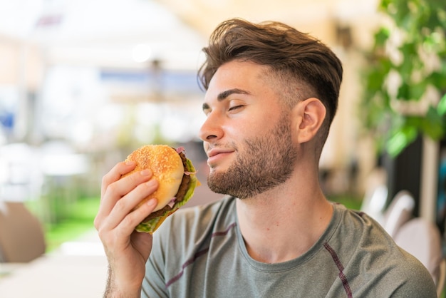 Giovane uomo bello che tiene un hamburger