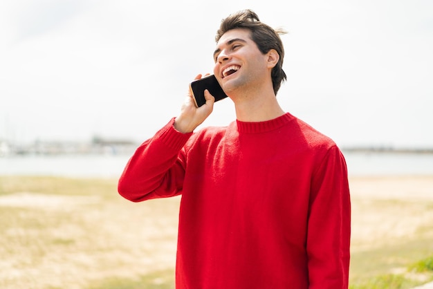 Giovane uomo bello che tiene una conversazione con il telefono cellulare