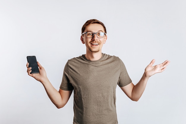 Giovane uomo bello che tiene uno smartphone e sorridente.