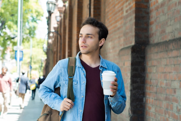 Giovane uomo bello con caffè usa e getta