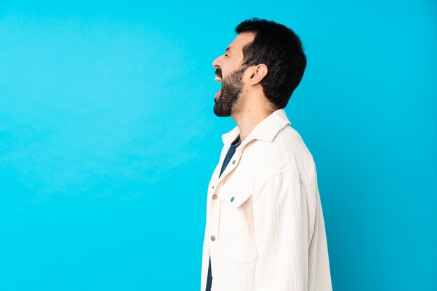 Giovane uomo bello con giacca di velluto bianco sopra l'azzurro che ride in posizione laterale