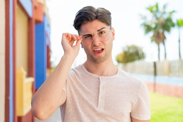 Giovane uomo bello con gli occhiali e l'espressione frustrata