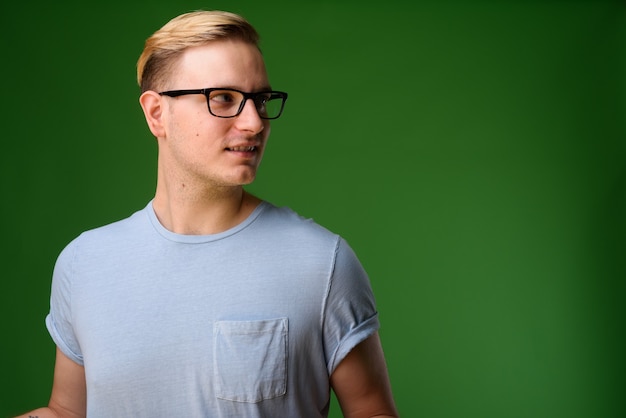 Giovane uomo bello con i capelli biondi su sfondo verde