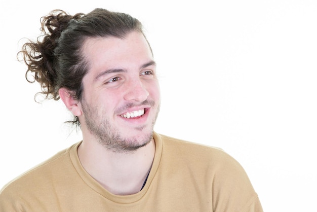 Giovane uomo bello con la barba capelli lunghi in piedi su sfondo bianco che guarda lontano al lato con il sorriso di espressione naturale che ride ragazzo