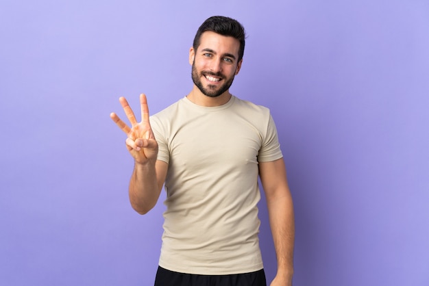 Giovane uomo bello con la barba felice e contando tre con le dita