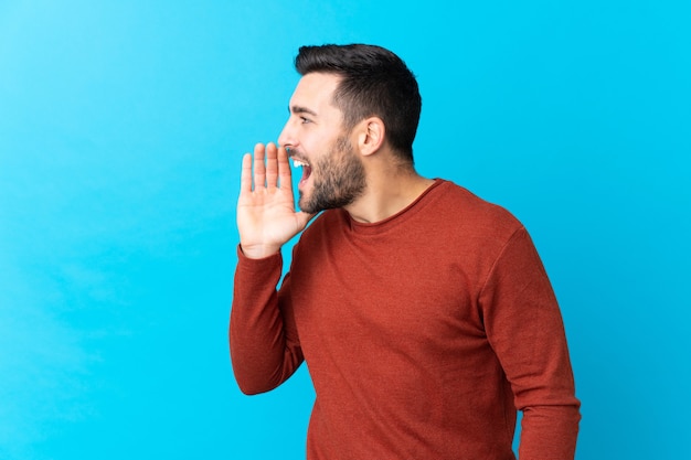 Giovane uomo bello con la barba isolata che grida con la bocca spalancata