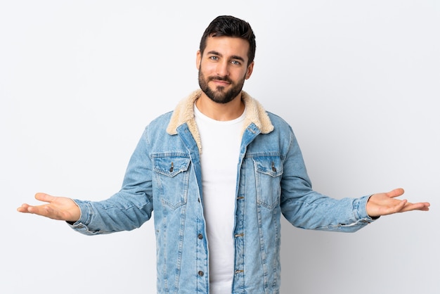 Giovane uomo bello con la barba isolata su bianco che ha dubbi