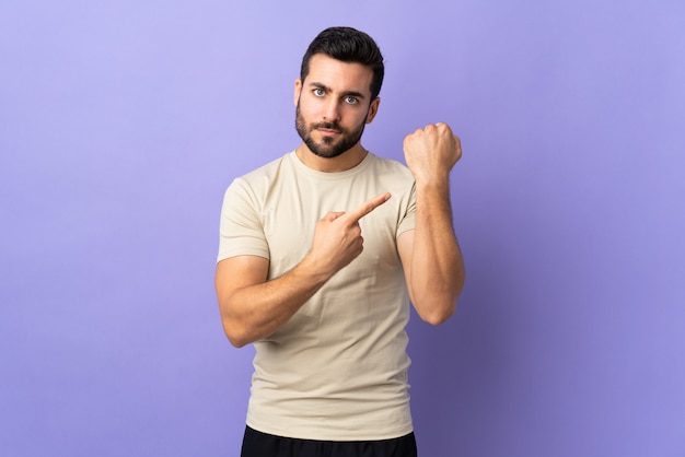 Giovane uomo bello con la barba sul muro facendo il gesto di essere in ritardo