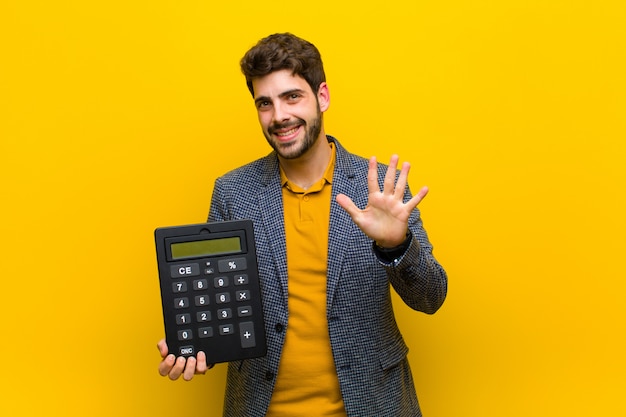 Giovane uomo bello con un calcolatore contro l'arancia
