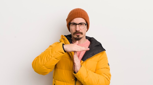 Giovane uomo bello con un cappotto contro il muro bianco