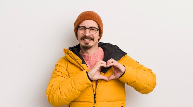 Giovane uomo bello con un cappotto contro il muro bianco