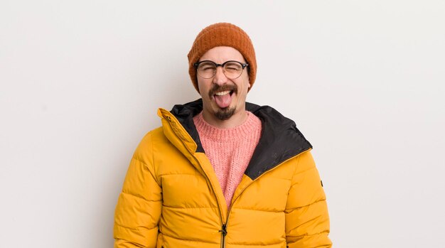 Giovane uomo bello con un cappotto contro il muro bianco