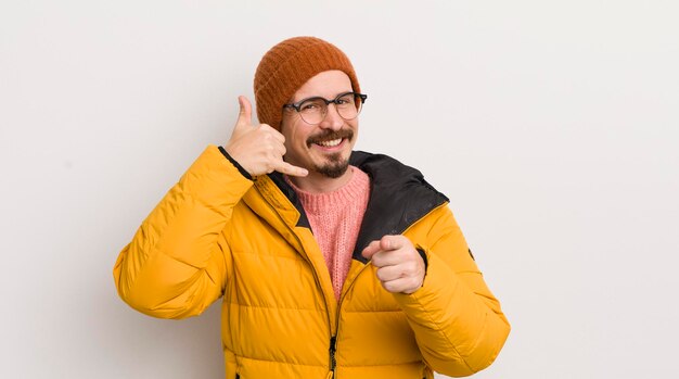 Giovane uomo bello con un cappotto contro il muro bianco