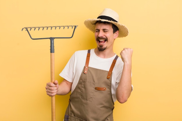 Giovane uomo bello con un concetto di agricoltore di rastrello