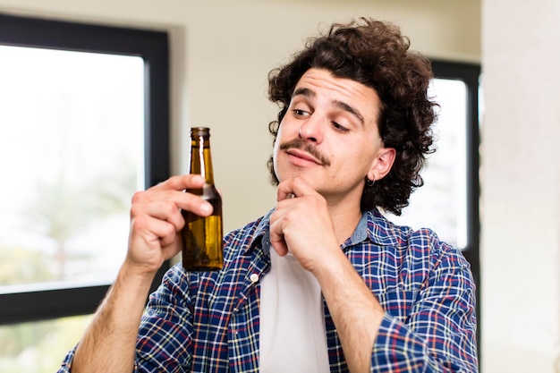 Giovane uomo bello con una birra a casa all'interno di casa