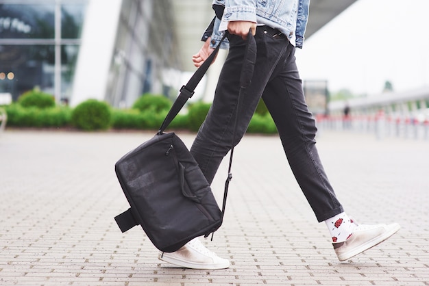 Giovane uomo bello con una borsa sulla spalla in fretta per l'aeroporto.